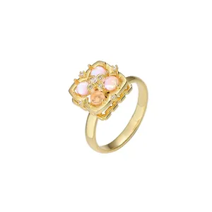 Eleganter goldener Ring mit quadratischem Rahmen, rosa opalisierenden Steinen und Zirkon
