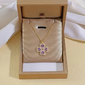 Detail of a gold clover necklace with purple heart gems in a premium jewelry gift box