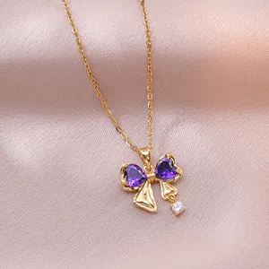 Detail of gold bow necklace featuring purple heart-shaped stones on pink silk fabric