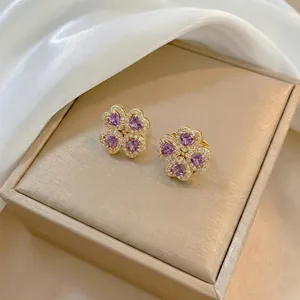 Detail of four-leaf clover stud earrings with purple heart stones and gold base
