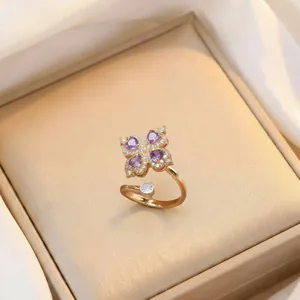 Détail d'une bague ajustable dorée ornée de zircons violets en forme de cœur