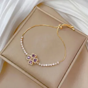 Detail of adjustable gold bracelet with purple clover pendant and white zircon stones