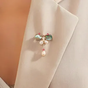 Broche papillon élégante avec perles et ailes en coquillage sur revers de veste beige