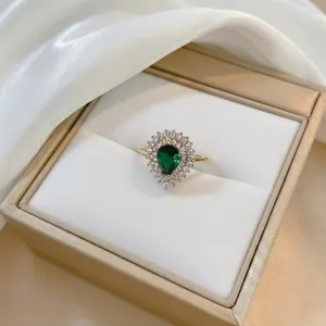 Edle goldene Halskette mit birnenförmigem Smaragd und Zirkonia-Halo auf weißer Seide