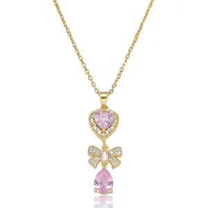 Close-up of golden necklace with pink heart and teardrop stones and bow pendant