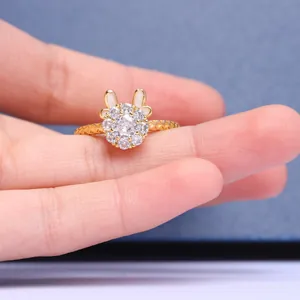 Primer plano de anillo dorado con orejas de conejo, flores de circón y banda texturizada