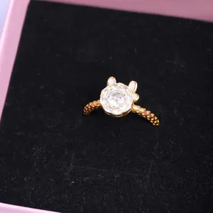 Vista macro de un anillo dorado con circonita transparente y un diseño de orejas lindas