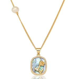 Détail du collier doré avec pendentif dauphin en nacre et perle blanche irrégulière