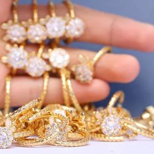 Primer plano de anillos de flor dorados con circonitas y detalles de banda texturizada