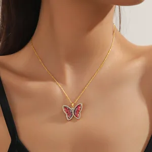 Close-up of golden bow necklace featuring red translucent wings and shimmering diamond border