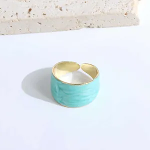 Detailed view of light blue marble enamel finish on a wide gold open adjustable ring