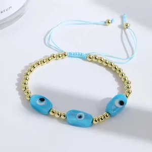 Detail of 18K gold-plated beads and blue evil eye charms on adjustable cord bracelet