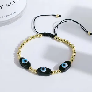 Detail of adjustable evil eye bracelet featuring gold beads and handcrafted woven black cord