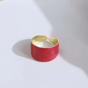 Detail of wide open ring featuring red embossed texture and polished gold inner surface