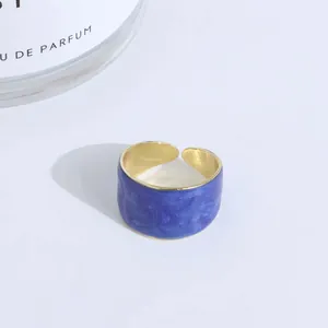 Macro view of wide adjustable open ring with blue marble enamel finish and gold inner band