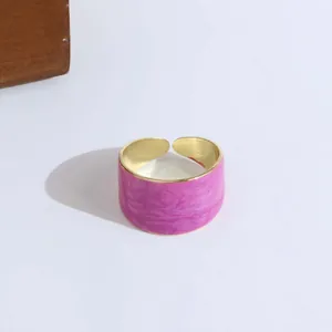 Macro detail of pink enamel wide open ring with polished golden metal inner band