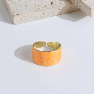 Exaggerated wide open ring featuring orange marble texture and golden metal accents