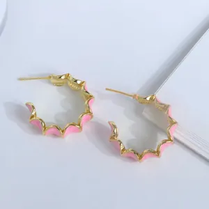 Vue détaillée de créoles ondulées plaquées or 18 carats avec émail rose et texture