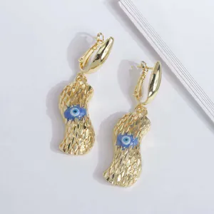 Detalle macro de pendientes de cacahuete bañados en oro 18K con ojo azul y textura