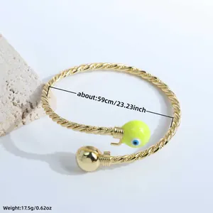 Twisted gold-plated cuff with yellow evil eye charm showing 59mm diameter detail