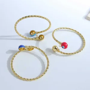 18K gold plated evil eye twist bangle featuring colorful enamel accents and open design