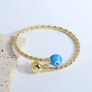 Detail of 18K gold-plated twisted rope bracelet with blue evil eye and gold bead