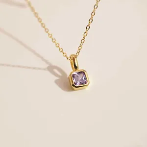 Gros plan d'un pendentif en pierre violette carrée sur une chaîne plaquée or 18 carats