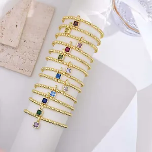 Macro detail of 18k gold beaded bracelets featuring colorful square zircon birthstone charms