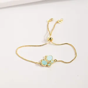 Détail macro du bracelet ajustable doré avec breloque papillon bleu et zircons étincelants