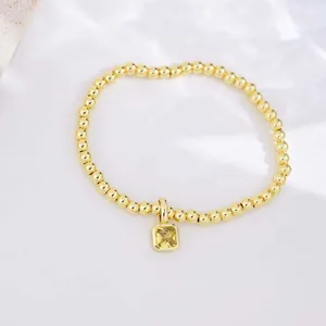 Close-up of 18k gold plated beaded bracelet with square yellow zircon pendant