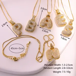 Détail macro de pendentifs alphabet dorés glacés sertis de zircons cubiques