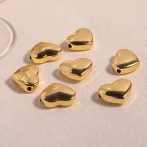 Macro detail of polished 18K gold heart-shaped metal beads with side holes for DIY jewelry