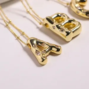 Detail of 3D balloon letter pendants with cubic zirconia inlay on gold satellite chains