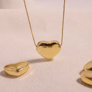 Detailed close-up of a high-polished 18K gold heart pendant with a delicate box chain