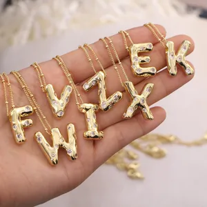 Detail of gold plated 3D initial necklaces with sparkling cubic zirconia on ball chains