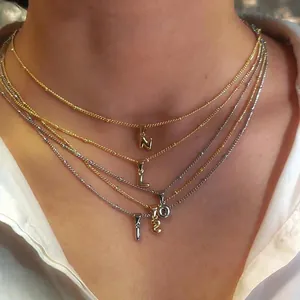 Close-up of layered gold and silver bubble initial pendants on necklaces for women
