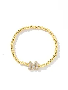 Detail of gold beaded bracelet with a zircon-encrusted bubble letter M pendant