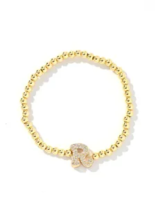 Macro detail of gold beaded bracelet featuring a micro-paved crystal letter R charm
