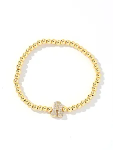 Detailed view of golden beaded bracelet featuring a shimmering zircon-paved bubble letter A