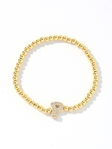 Detail of golden beaded bracelet with crystal-studded letter P balloon charm