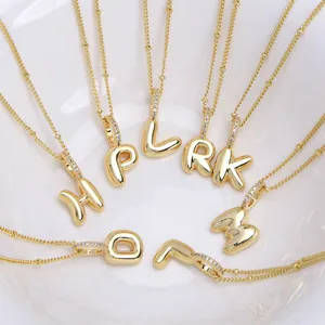 3D balloon alphabet necklace pendants in 18k gold plated finish inside a white bowl