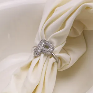 Macro shot of silver letter P ring with pave cubic zirconia on textured fabric
