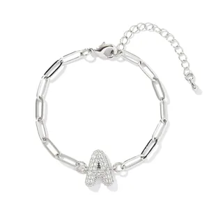 Bracelet chaîne trombone argentée avec pendentif lettre A serti de strass sur fond blanc