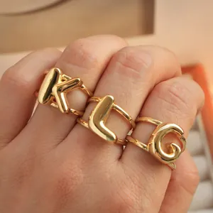 Macro-opname van drie gouden bubble letter ringen K, L en G met dubbele rij banden