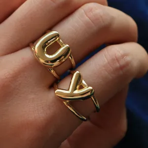 Detail van vergulde puffy ballonletter U en V ringen met dubbele banden aan de vinger
