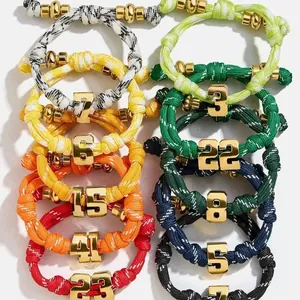 Detail of adjustable braided bracelets with gold 18K plated 3D number charms in various colors