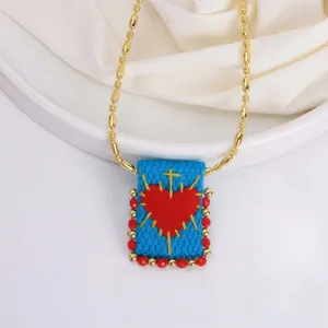 Close-up of 18K gold beaded chain with a woven blue rectangular heart pendant