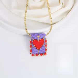 Detail of 18K gold chain with hand-woven rectangular pendant and red heart motif