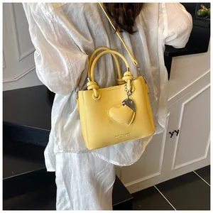 Détail du sac seau jaune en cuir grainé avec pendentif cœur et bandoulière amovible