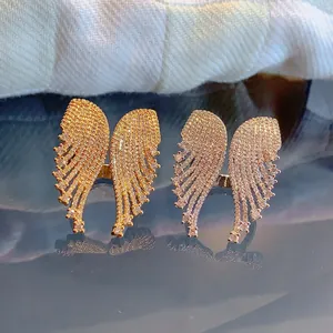 Close-up of gold and rose gold angel wing rings with pavé zircon stones on mirror base